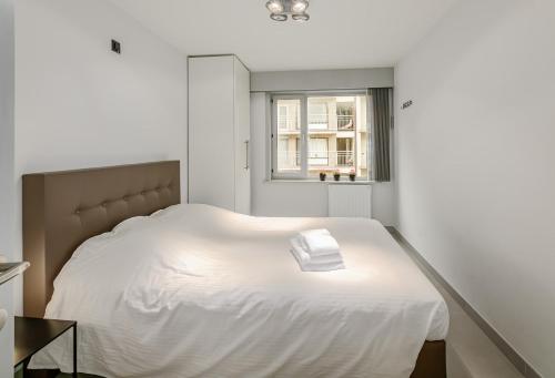 ein weißes Bett in einem Zimmer mit Fenster in der Unterkunft Wielingen 0302 in Oostduinkerke