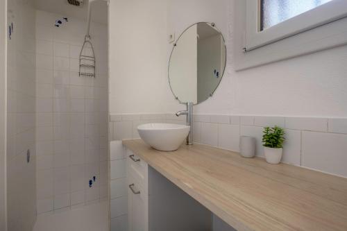 une salle de bain avec un lavabo et un miroir sur un comptoir dans l'établissement Rez de jardin à 400m de la Plage pour 4, à Pornic