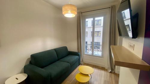 un salon avec un canapé vert et une fenêtre dans l'établissement Appartement lumineux proche Saint-Lazare - 8P, à Paris