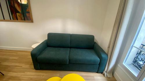 une chaise verte assise dans une pièce à côté d'une fenêtre dans l'établissement Appartement lumineux proche Saint-Lazare - 8P, à Paris