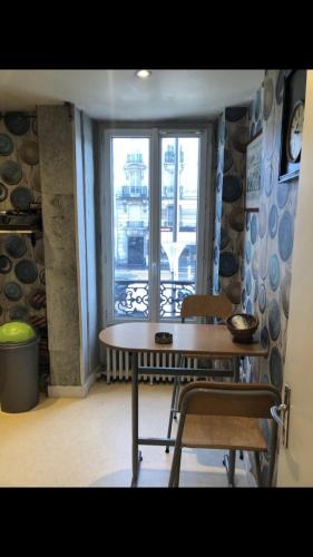 une table et des chaises dans une pièce avec une fenêtre dans l'établissement Appartement paris 14, à Paris