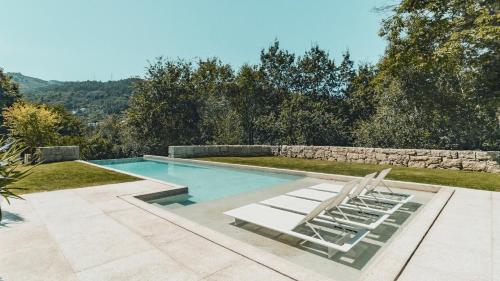 a swimming pool with two lounge chairs in a backyard at Casa da Cascata in Geres