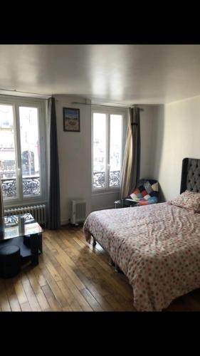 une chambre avec un lit et deux fenêtres dans l'établissement Appartement paris 14, à Paris