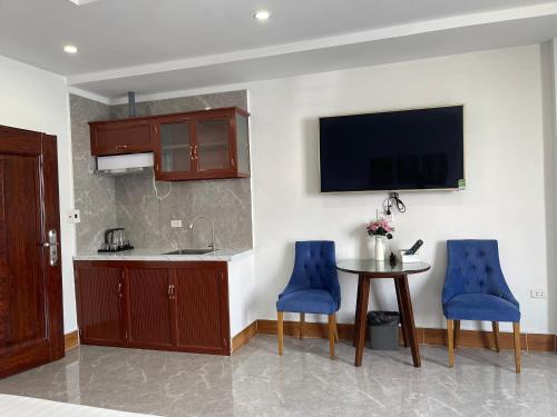 a kitchen with a table and blue chairs and a tv at IVY Homestay in Hai Phong