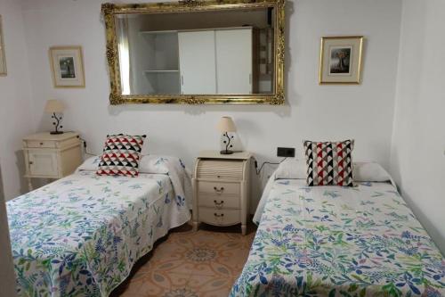 1 Schlafzimmer mit 2 Betten und einem Wandspiegel in der Unterkunft Casa preciosa con vistas in Granada