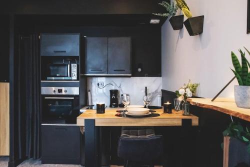 une cuisine avec des armoires noires et une table en bois dans l'établissement LOVE ROOM, La Douce Angevine, à Angers