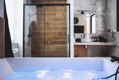 La salle de bains est pourvue d'une baignoire et d'une douche vitrée. dans l'établissement LOVE ROOM, La Douce Angevine, à Angers