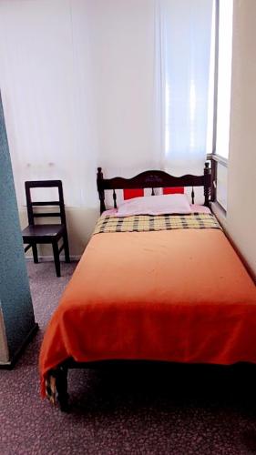 Un dormitorio con una cama con una manta naranja. en HOTEL OASIS DOS MAX, en Ipiales