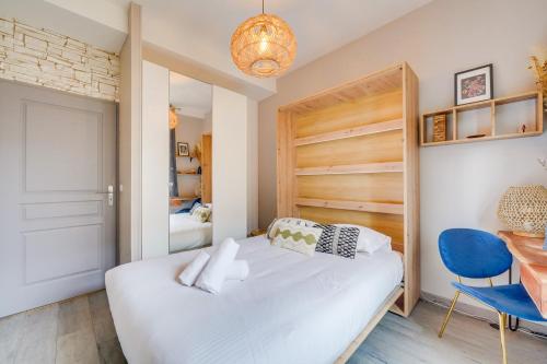 une chambre avec un lit blanc et une chaise bleue dans l'établissement Le Précieux - Appt Place de la Victoire, à Bordeaux