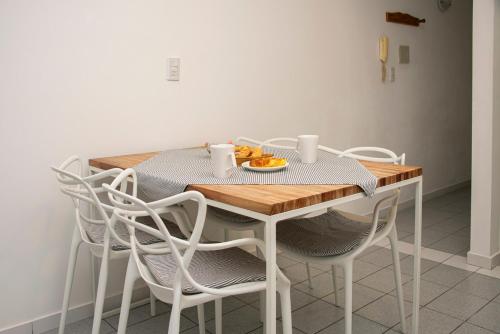 una mesa con sillas y un plato de fruta. en Departamento Blanco en Tandil