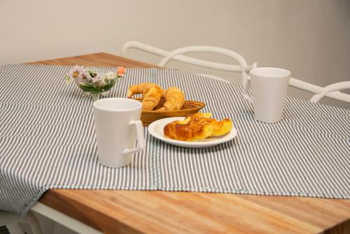 una mesa con un plato de comida y dos tazas en Departamento Blanco en Tandil