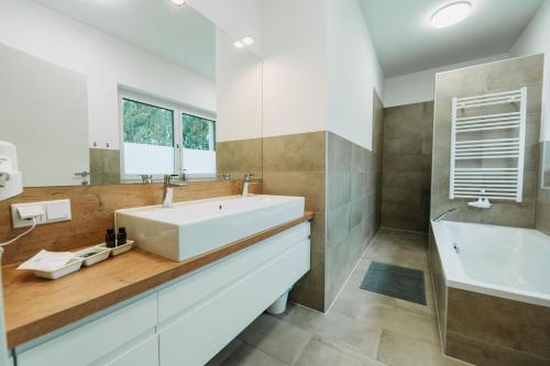 a bathroom with a large white sink and a tub at Weingut Zweytick Lodge Vinoment in Ehrenhausen