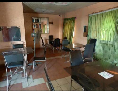 un comedor con mesas, sillas y cortinas verdes en Hibis k hotel (green gate), en Lagos