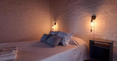 a white bedroom with a bed with two pillows at Palmeras Appart Hotel in Chascomús