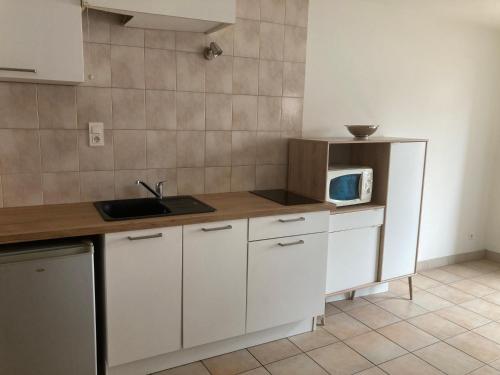 uma cozinha com armários brancos e um micro-ondas no balcão em Au bon lieu em Bouloc