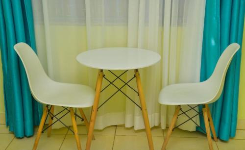 twee witte stoelen en een witte tafel voor de gordijnen bij The O,S Homestay in Chuka