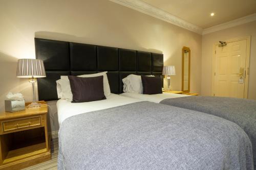a bedroom with two beds and a large headboard at Waterton Park Hotel in Wakefield