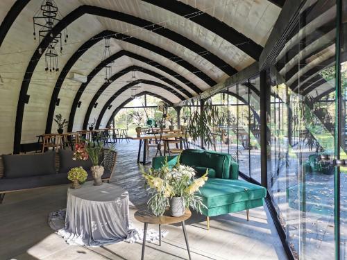 una sala de estar con un sofá verde y mesas. en Kupolmāja Ārpus laika - Domehouse in the forest en Tīnūži