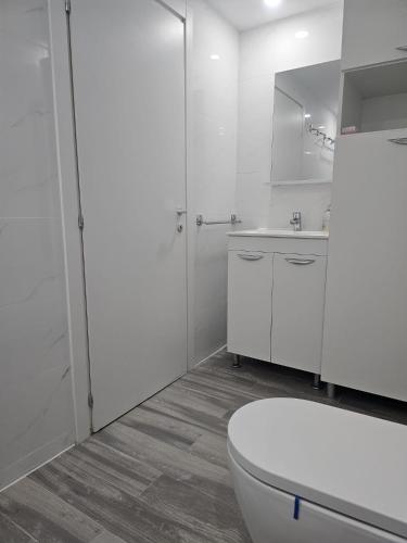 a white bathroom with a toilet and a sink at Sea View Apartments Olimp Etajul 9 in Olimp