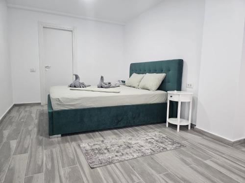 a bed with a green headboard in a room at Sea View Apartments Olimp Etajul 9 in Olimp