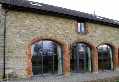 een bakstenen gebouw met vier ramen en een groep daarvan bij Swallows Swoop at Tove Valley Cottages in Towcester