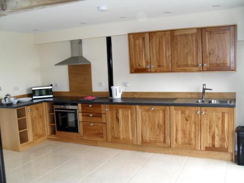 cocina con armarios de madera y fogones en Swallows Swoop at Tove Valley Cottages en Towcester