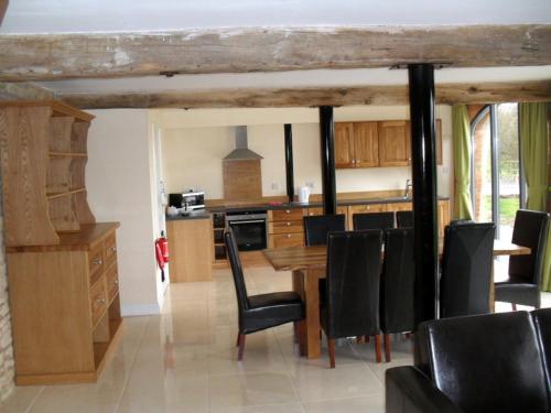 a kitchen with a wooden table and black chairs at Swallows Swoop at Tove Valley Cottages in Towcester