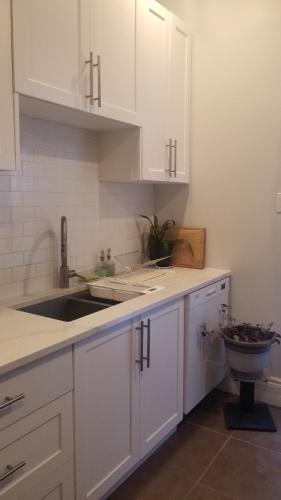 a kitchen with white cabinets and a sink at Tina's gem in Ottawa
