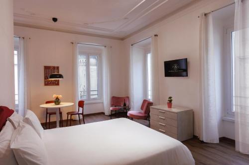 1 dormitorio con 1 cama blanca, mesa y sillas en Residence Piazza Giotti 8, en Trieste