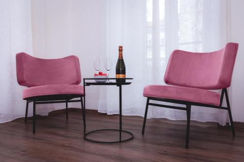 dos sillas rosas y una botella de vino en una mesa en Residence Piazza Giotti 8 en Trieste