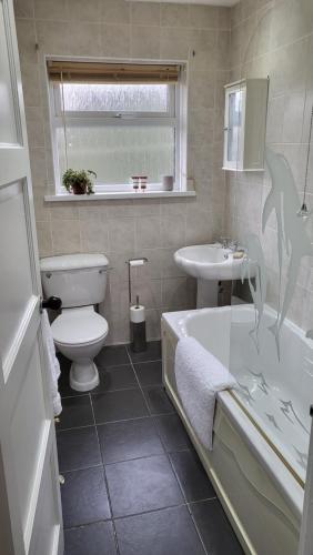 a bathroom with a toilet and a tub and a sink at Gortree at Castlerock in Castlerock