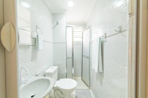 een witte badkamer met een toilet en een wastafel bij Local aconchegante e tranquilo. in Sao Paulo