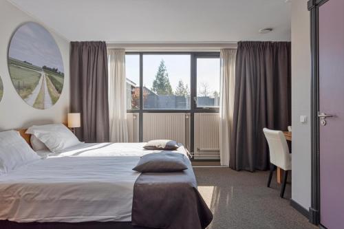 een slaapkamer met een bed, een bureau en een raam bij Hunzego Hotel in Uithuizermeeden