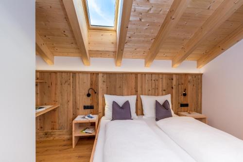 a bedroom with a large white bed with wooden walls at Bäckerhof in Tesido