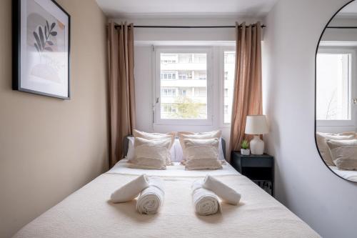 a bedroom with a bed with white pillows and a window at Appartement Charmant à Levallois in Levallois-Perret