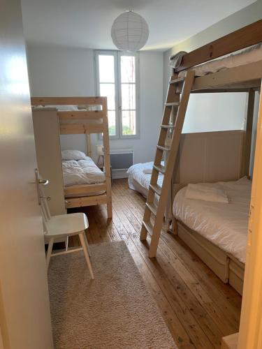 sypialnia z 2 łóżkami piętrowymi i krzesłem w obiekcie Gîte Petite Rousserie sur domaine La Rousserie w mieście Cadillac-en-Fronsadais