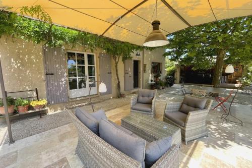 um pátio com sofás, uma mesa e cadeiras em Comfortable house with large garden and jacuzzi em Rognes
