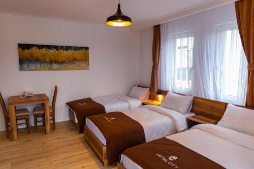 Zimmer mit 3 Betten, einem Tisch und einem Fenster in der Unterkunft Hotel City Star in Pristina