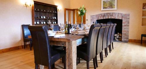 a dining room with a table with chairs and a fireplace at Wooladon House in Lifton