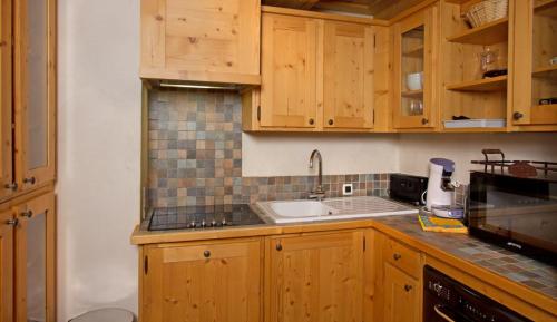 une cuisine avec des armoires en bois et un évier dans l'établissement Cortina - 52 - Appart lumineux - 8 pers, à Les Deux Alpes