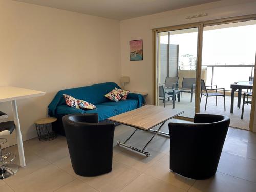 un salon avec un canapé bleu et une table dans l'établissement Bastia 2p neuf vue mer grande terrasse, à Bastia