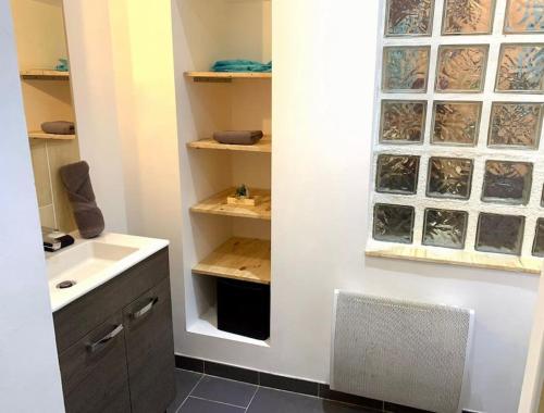 a bathroom with a sink and a window and shelves at "Pascal 1" Eglise St Louis - Studio Cosy Quartier Haut in Sète