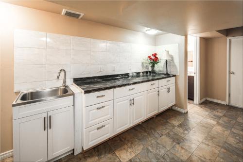 eine Küche mit weißen Schränken und einem Waschbecken in der Unterkunft A-Home by chinook mall and Heritage park in Calgary