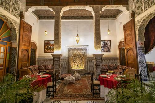 a restaurant with tables and chairs and a fireplace at Riad Jamal in Fès