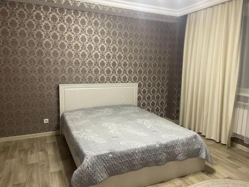 a bedroom with a bed and a wall at Квартира in Pavlodar