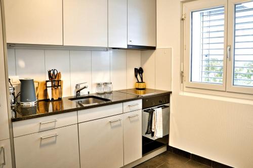 een keuken met witte kasten, een wastafel en een raam bij Studio 5 places à deux pas du Lac in Territet