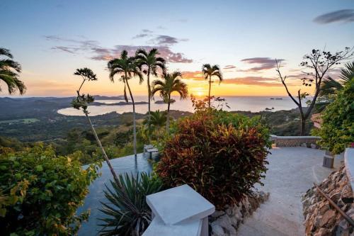 a sunset view of the ocean and palm trees at Beautiful House with Sweeping Ocean Views, Modern Design, and a Private Infinity Pool in Potrero