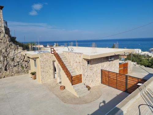 un edificio in pietra con scala e vista sull'oceano di Pasithea Luxury house a Archangelos