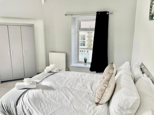 a white bed in a room with a window at Cozy Home Afan Valley Mountain Retreat - Sleeps -8 in Glyncorrwg