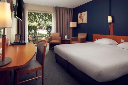 een hotelkamer met een bed en een bureau en een tafel en stoelen bij Hotel De Werelt Garderen in Garderen